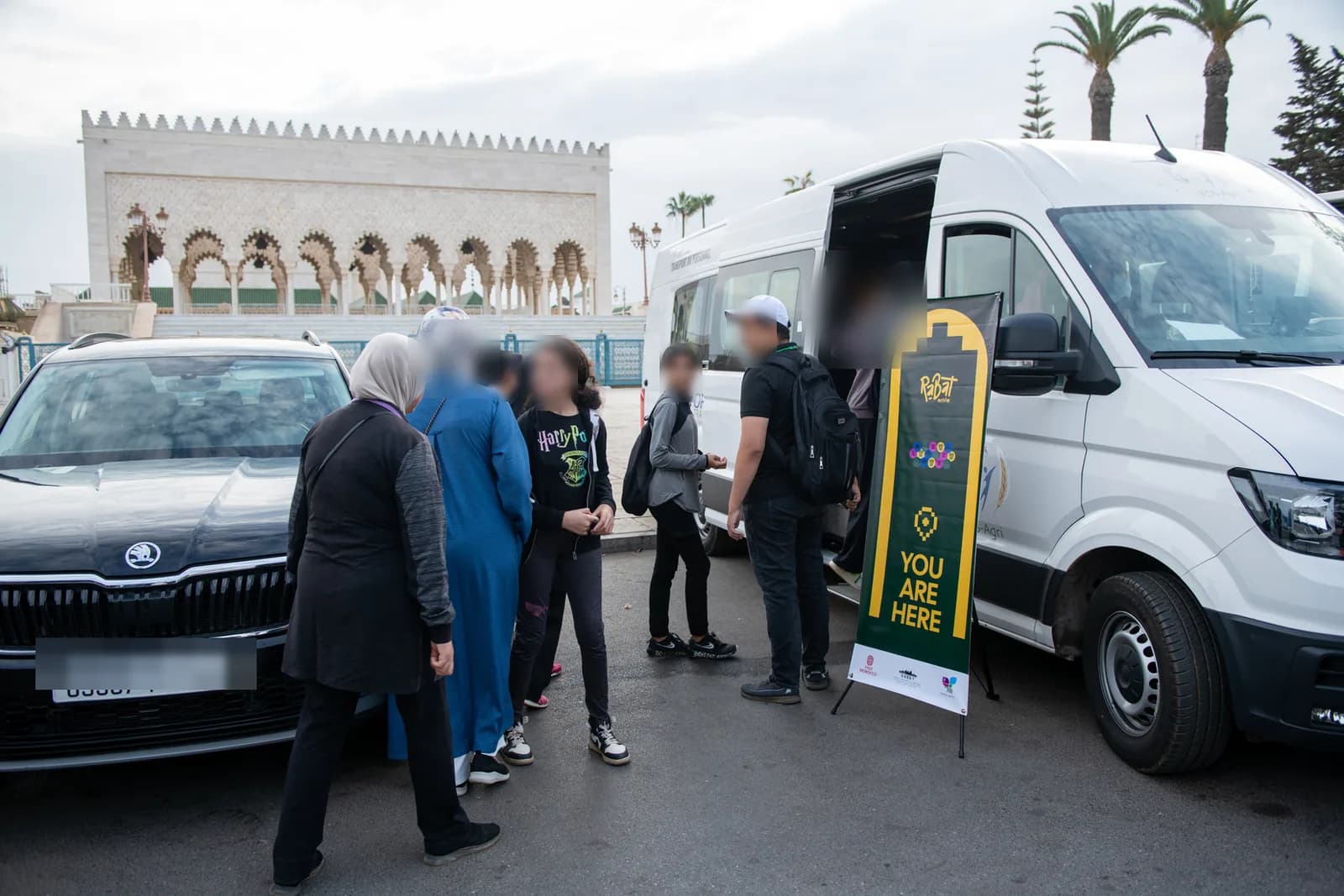 Departure for the Maamora Challenge at the Mausoleum of Mohammed V: participants and a minibus beside the event signage.